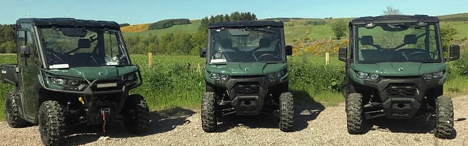 Three Can-Am Traxter side-by-side vehicles parked in a field